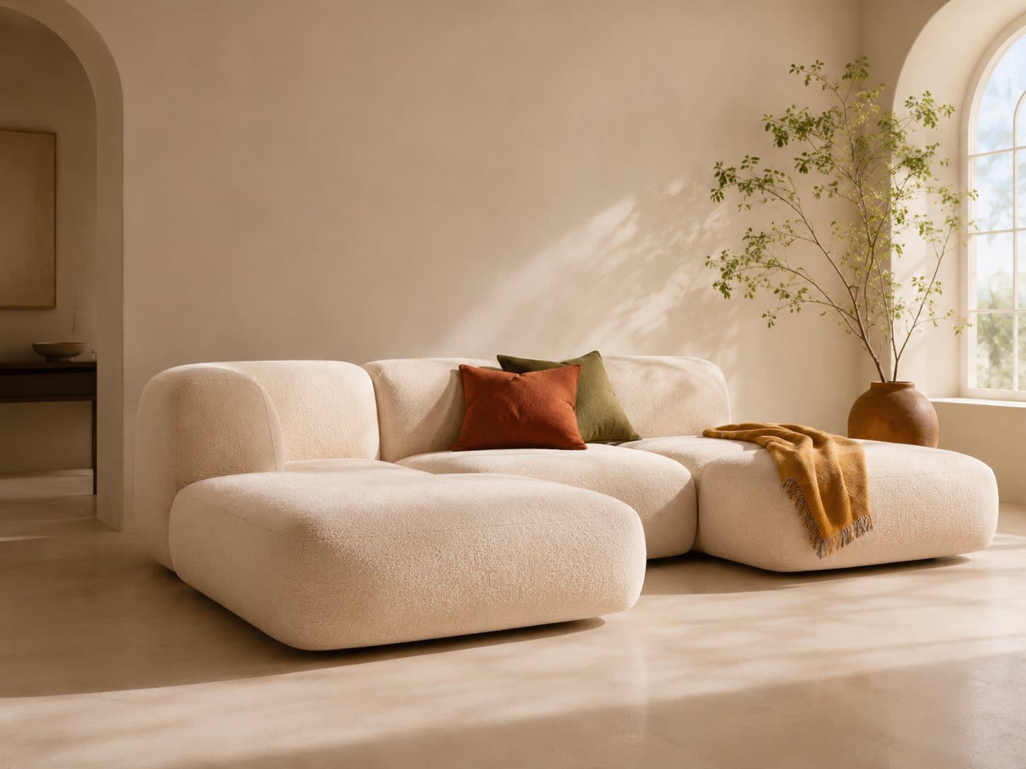 The Duna modular sofa in cream bouclé with terracotta and ochre cushions